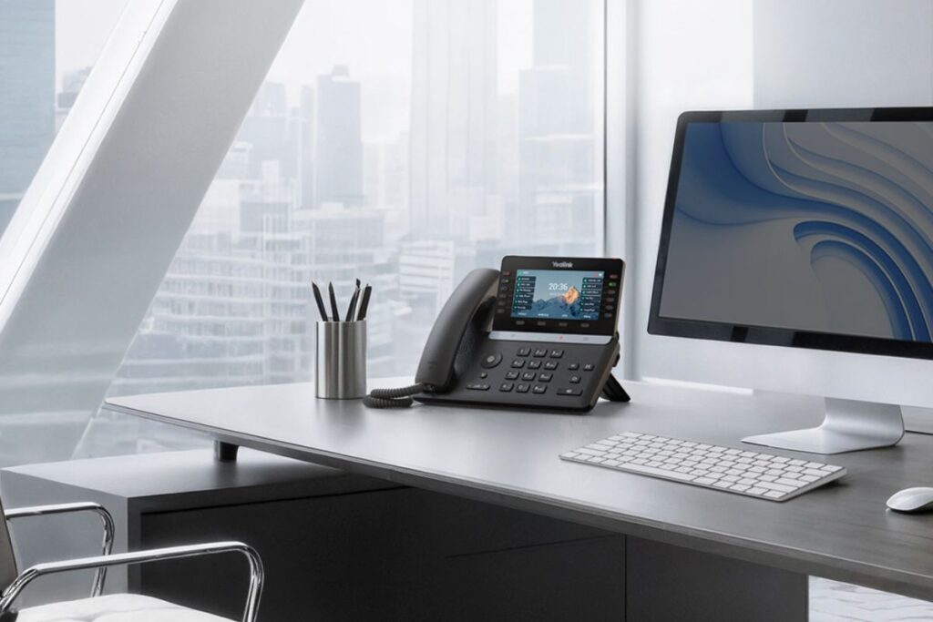 Yealink SIP-T85W on office desk (Hosted PBX) Yealink SIP-T85W desk phone on a modern office desk, connected to AHS hosted PBX service